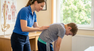 Fizjoterapeuta bada kręgosłup dziecka pod kątem skoliozy
