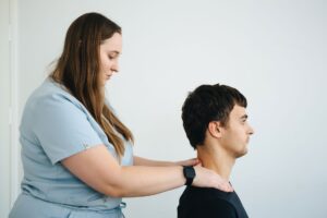 Fizjoterapia bólu głowy szyjnopochodnego – terapeuta wykonuje mobilizację kręgosłupa szyjnego